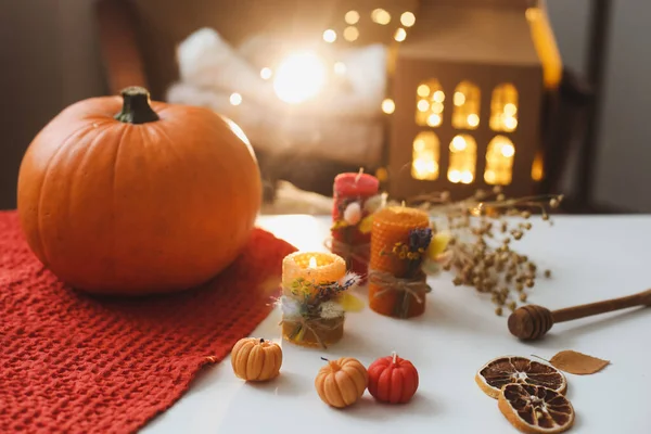 Cozy autumn composition. Pumpkin, wax candles, leaves. Hygge lifestyle, cozy autumn mood. Halloween, Happy Thanksgiving concept