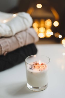 Noel arkaplanı. Mum, örgü süveter, yılbaşı süslemeleri ve arka plan ışıkları. Noel sıcacık havası hala hayat