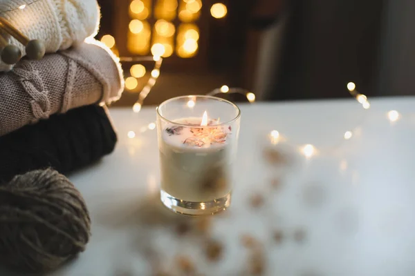 Sfondo natalizio. Candela, maglione lavorato a maglia, decorazioni natalizie e sfondo luci bokeh. Natale umore accogliente natura morta — Foto Stock