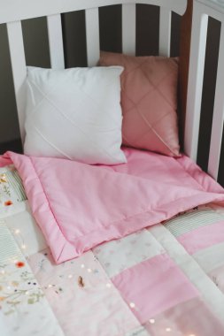 Pembe battaniyeli rahat bir bebek karyolası. Bebek yatağı. Bebek beşiği, kapat. Çocuk yuvası için tekstil. Uyku ve uyku zamanı.