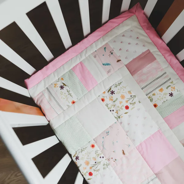 Acogedora cuna con manta patchwork rosa. Ropa de cama de bebé. Cuna, de cerca. Textil para guardería infantil. Siesta y tiempo de sueño —  Fotos de Stock