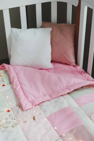 Acogedora cuna con manta patchwork rosa. Ropa de cama de bebé. Cuna, de cerca. Textil para guardería infantil. Siesta y tiempo de sueño —  Fotos de Stock