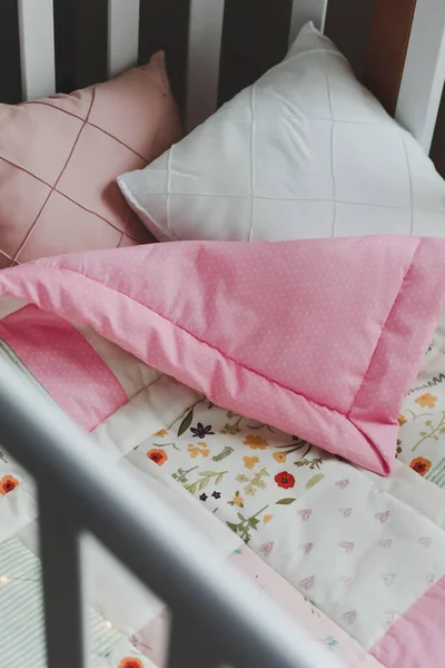 Acogedora cuna con manta patchwork rosa. Ropa de cama de bebé. Cuna, de cerca. Textil para guardería infantil. Siesta y tiempo de sueño —  Fotos de Stock