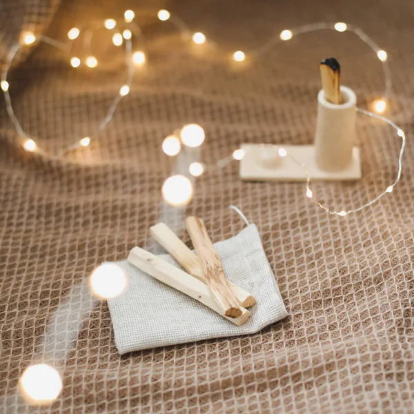 Palo Santo stick in candlestick. Healing, meditation, relaxation concept. Aromatic sticks on dark background. Cozy evening at home