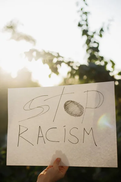 Kvinna Med Vitbok Med Texten Stoppa Rasismen Mot Bakgrund Träd — Stockfoto