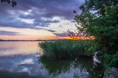gün batımı ve göl üzerinde kara bulutlar