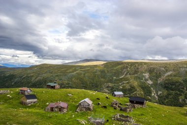 Norveç 'te Aurlandsvangen yakınlarındaki dağ yolunda ahşap kulübelerin üstündeki bulutlar.