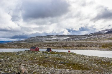 Norveç 'te Aurlandsvangen yakınlarındaki dağ yolunda ahşap kulübelerin üstündeki bulutlar.