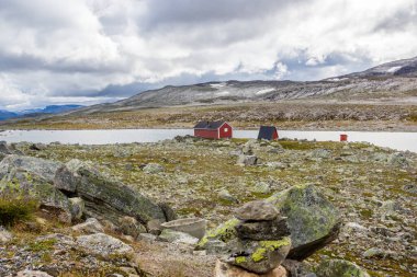 Norveç 'te Aurlandsvangen yakınlarındaki dağ yolunda ahşap kulübelerin üstündeki bulutlar.
