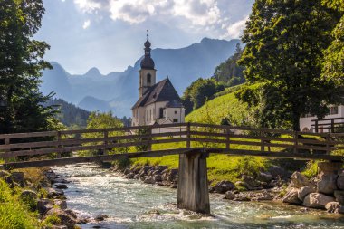 Nehir kıyısında güneşli bir gün. Ramsau, Almanya 'daki kilisenin yanında.