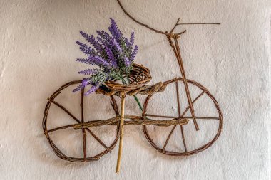 Eski bir duvarda asılı ince ağaç dalları kullanılarak el yapımı küçük bisiklet süs üzerinde Mor kır çiçeği