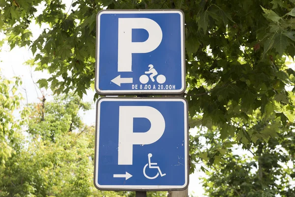 Image of a street sign is seen in this picture. The sign showcases two symbols, one for physcially challenged and the other for cyclists. The signboard is blue in color.