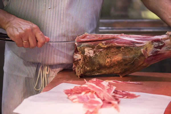 Bir kasap et et kasap bıçağıyla keserek görülür. Eti taze görünüyor ve kesmek sonra satışa hazırdır. O bir şerit önlük giyen görülür.