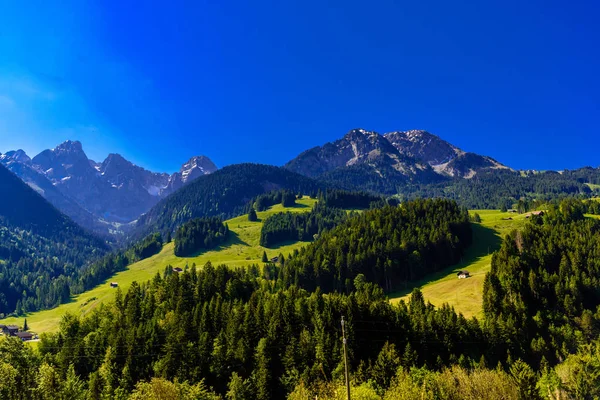 Montanhas com prados, floresta e céu azul em Flendruz, Rougemo — Fotografia de Stock