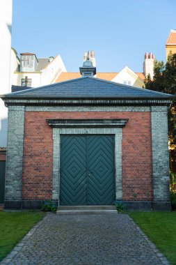 pavement and green grass near small building with wooden doors, copenhagen, denmark clipart