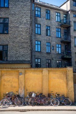 building and parked bicycles near yellow stone wall in Copenhagen, Denmark clipart