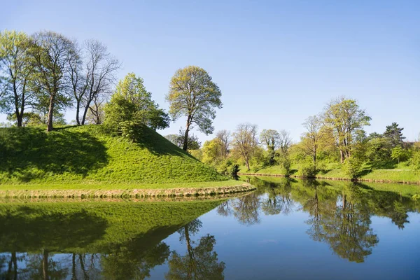 Beautiful green hills, trees and bushes reflected in water, copenhagen, denmark — Stock Photo