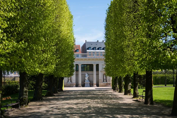 Belle ruelle avec des arbres verts et bâtiment historique avec des colonnes et des statues en copenhagen, Danemark — Photo de stock