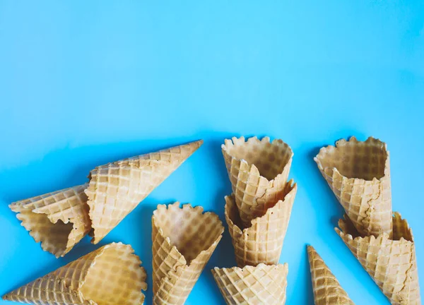 Sweet wafer cone for ice cream on blue background, copy space