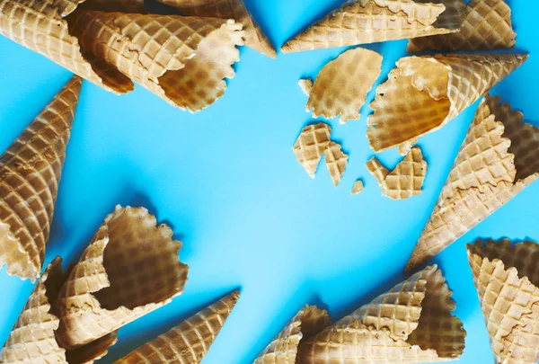 Sweet wafer cone for ice cream on blue background, copy space