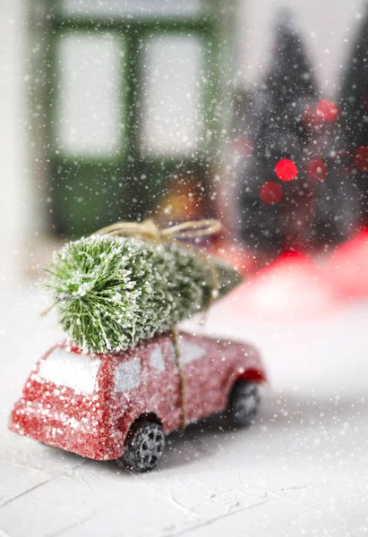 Red retro toy car delivering Christmas Tree. Holiday card