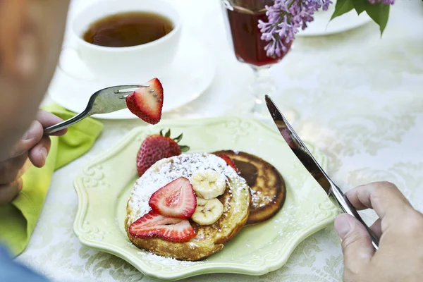 Pancakes with strawberry and banana. Man eating a pancakes. Summ