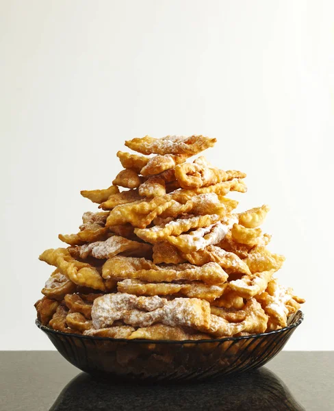 Buñuelos espolvoreados con azúcar glaseado. Frappe o chiacchiere. Comerciar —  Fotos de Stock