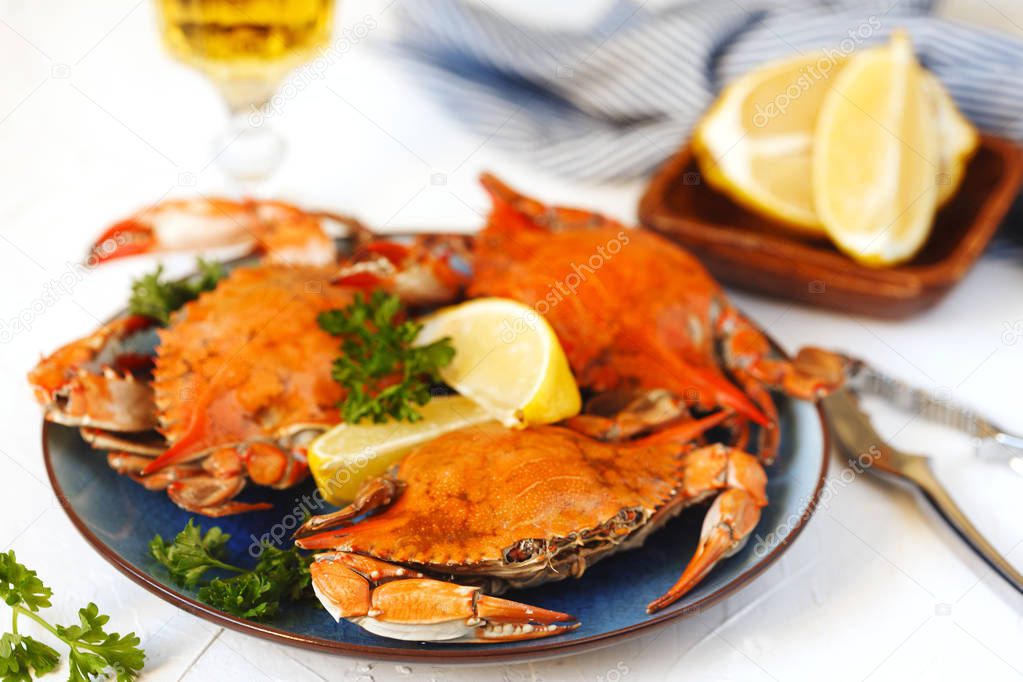 Cooked crabs served on plate with lemon and parsley.