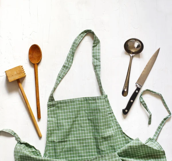 Grün karierte Schürze mit Küchenutensilien. — Stockfoto