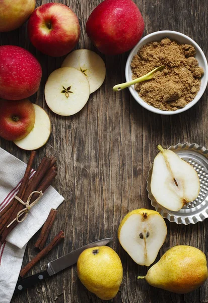 Manzanas, peras, palitos de canela y azúcar morena sobre fondo de madera — Foto de Stock