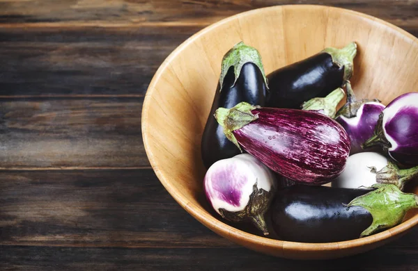 Verse aubergines van verschillende kleur en variëteit in houten schaal op — Stockfoto