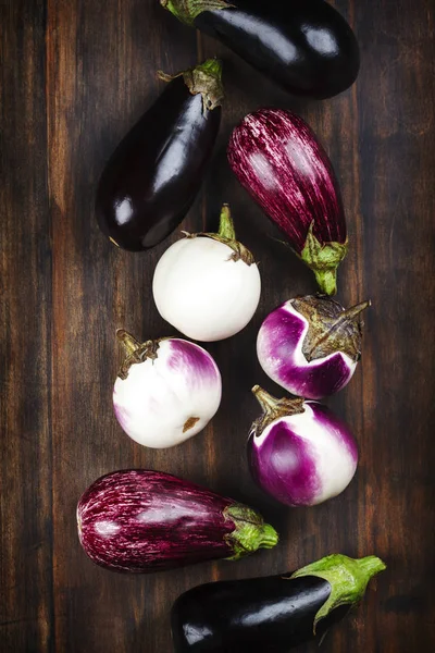 Fresh eggplants of different color and variety on a wooden backg — Stock Photo, Image