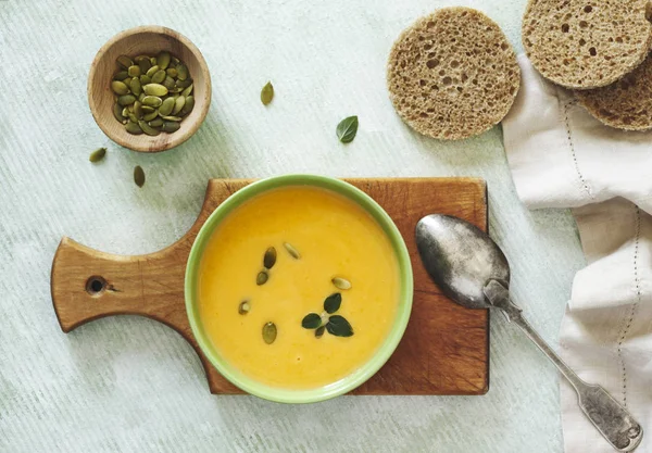 Pumpkin creamy soup on light green background — Stock Photo, Image