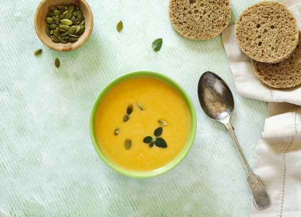 Pumpkin creamy soup on light green background