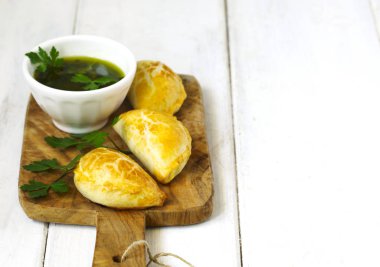 Ahşap masa üzerinde chimichurri soslu Empanadas