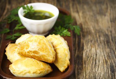 Ahşap masa üzerinde chimichurri soslu Empanadas