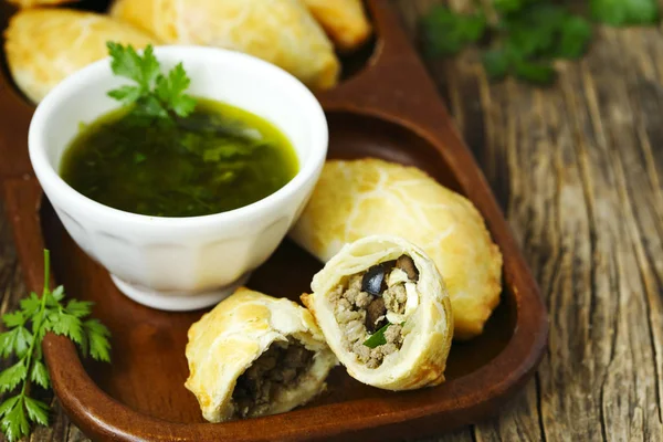 Empanadas met Chimichurri saus op houten tafel — Stockfoto