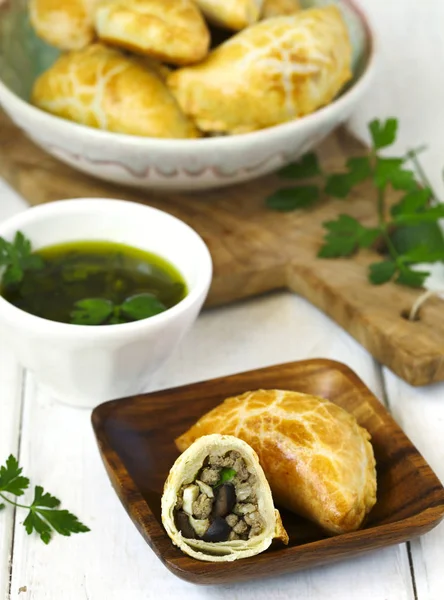 Empanadas with chimichurri sauce on wooden table — Stock Photo, Image