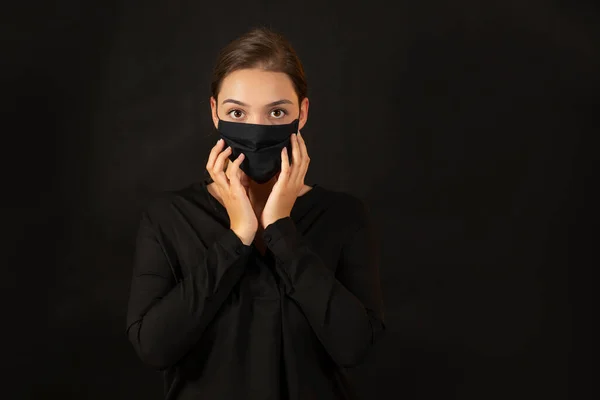Brunette jeune femme touchant son visage dans un masque de protection. — Photo
