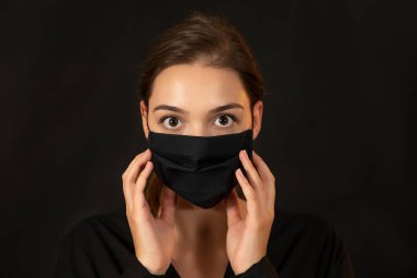 Siyah koruyucu maskeli çekici genç bir kadın..
