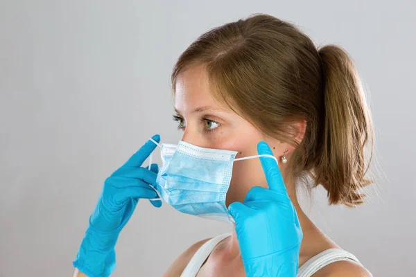 Young woman with blond hair putting on face mask from side view — Stock Photo, Image