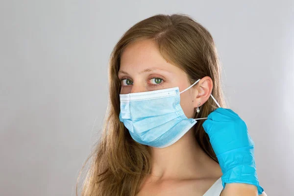 Young blonde woman putting on face mask in studio. — Stock Photo, Image