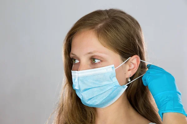 Young woman putting on face mask with white background. — Stock Photo, Image