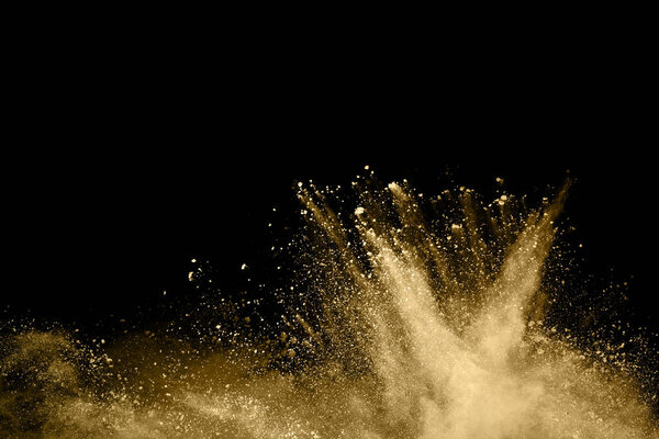 Golden powder explosion on black background. Freeze motion.