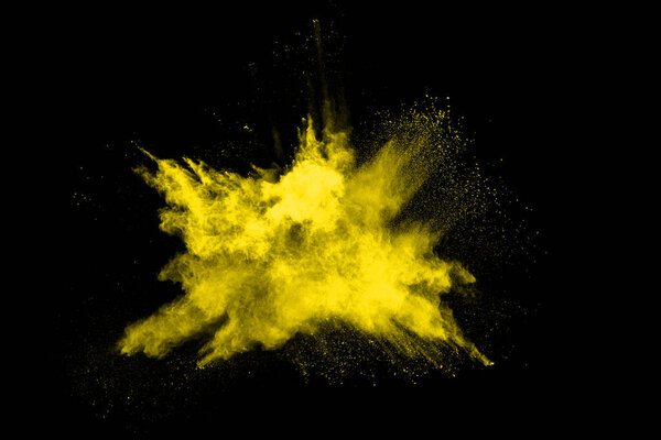 Замораживание движения взрыва желтой пыли на черном фоне.