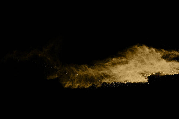 Golden powder explosion on black background. Colored cloud. Colorful dust explode. Paint Holi.