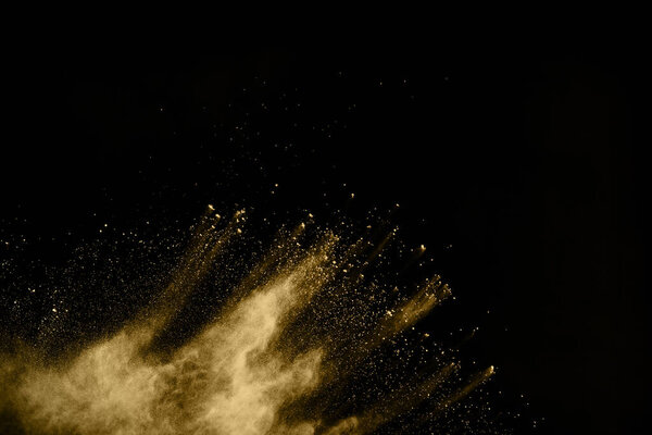 Golden powder explosion on black background. Colored cloud. Colorful dust explode. Paint Holi.