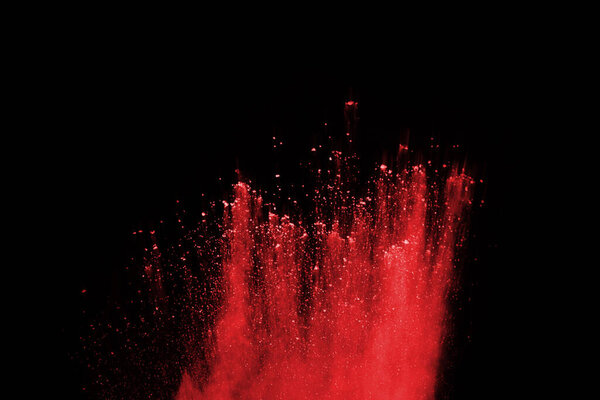 Взрыв красного порошка на черном фоне. Замораживание движения взрывающегося красного порошка.