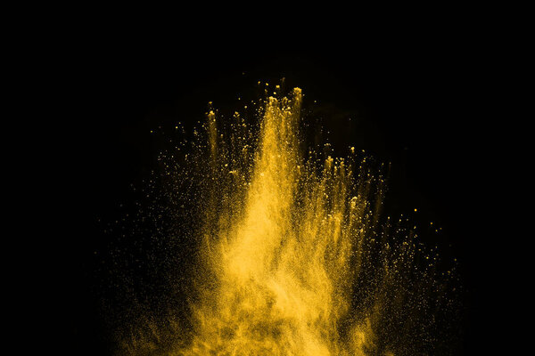 Freeze motion of yellow dust explosion isolated on black background.
