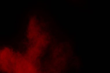 Siyah arka planda soyut kırmızı toz patlaması. Siyah arka planda soyut kırmızı toz sıçramış. Patlayan kırmızı barutun hareketsiz hareketi.